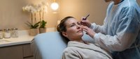 Professional cosmetic injection procedure with female patient receiving facial treatment from medical practitioner in modern clinic setting.