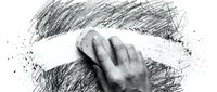 Hand erasing pencil marks with white eraser on textured paper surface. Creative artistic process of correction and refinement in drawing and sketching work.