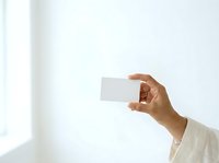 Hand holding blank white business card against light background, suitable for corporate branding, identity design, and marketing mockups.