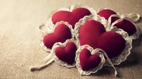 Red fabric hearts with natural rope ties on burlap texture for romantic crafts, Valentine's Day decorations, and handmade gift projects.