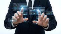 Business professional in dark suit manipulating holographic data analytics dashboards with charts, graphs and financial metrics floating in digital space.
