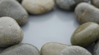 Smooth river stones arranged in circle on white background creating peaceful zen meditation space for wellness and relaxation concepts.