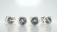 Four transparent glass spheres containing swirling blue galaxy patterns arranged in row on white surface for cosmic design projects.