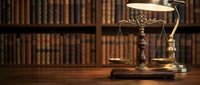 Scales of justice and gavel on wooden desk in law library with vintage books background for legal services and attorney office concepts.