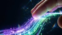 Hand reaching toward flowing digital data streams with glowing particles and network connections in purple and green colors on dark background.