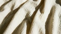 Neutral beige and white striped fabric texture with soft shadows, suitable for backgrounds, textile design, and interior decoration projects.