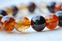 Elegant amber and black glass beads in close-up macro shot showing transparent spheres with natural light reflections and delicate internal patterns.