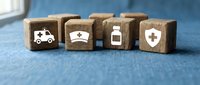 Healthcare medical insurance concept with wooden blocks showing ambulance hospital medicine and shield symbols on blue background.
