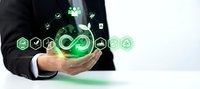 Businessman holding glowing green circular economy icons with infinity symbol, representing sustainable development and eco-friendly business strategy.