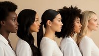 Diverse group of women in profile view wearing white shirts against neutral background representing unity, teamwork and multicultural beauty.