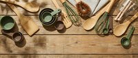 Vintage kitchen utensils and cookware arranged on rustic wooden background with copy space for culinary design projects and cooking concepts.