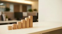 Wooden blocks arranged in ascending staircase pattern on desk, symbolizing growth, progress and business success in modern office environment.