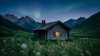 Abandoned wooden cabin glowing with warm light in remote mountain valley at night, surrounded by wildflowers and green meadows under starry sky with aurora borealis.
