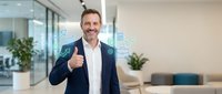 Confident middle-aged Caucasian businessman giving thumbs up with digital technology icons overlay in modern office environment for business success concepts.
