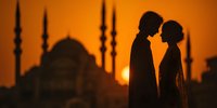 Romantic couple silhouette embracing at sunset with mosque minarets in background creating intimate moment for wedding and love concepts.