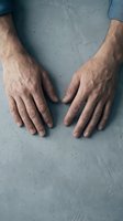 Senior man hands on concrete surface showing aging skin texture and wrinkles for healthcare and elderly care concepts.