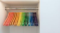 Colorful rainbow clothes hangers organized in closet wardrobe displaying vibrant spectrum from red to purple for home organization and storage solutions.