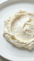 Creamy whipped butter or cream cheese spread on white plate, ready for baking, cooking, or food styling projects.