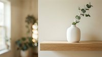 White ceramic vase with eucalyptus branches on wooden shelf in minimalist interior. Suitable for home decor, interior design, and lifestyle content.