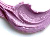 Pink creamy cosmetic texture smear on white background, close up macro shot of smooth swirled skincare product sample showing luxurious consistency.