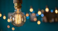 Vintage Edison bulb glowing with warm filament against blurred bokeh lights background for cozy interior design and atmospheric lighting concepts.
