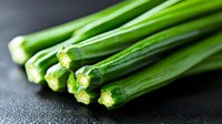 Fresh green onions with vibrant stems and white roots clustered together on dark surface, suitable for culinary, food styling, and recipe content.