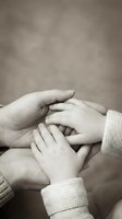 Tender moment of family hands joined together in sepia tones showing unity, support and connection between generations in warm intimate setting.