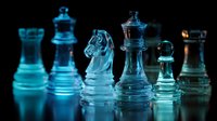 Transparent glass chess pieces illuminated with blue light against dark background, creating dramatic contrast for strategic game concept.