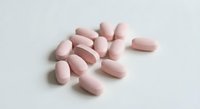 Pink oval tablets scattered on white background for pharmaceutical and healthcare concepts.