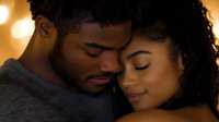 Young African American couple sharing intimate moment with closed eyes and gentle smiles, faces close together against warm glowing bokeh background.