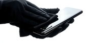 Close-up of hands in black gloves holding and using a smartphone against white background for technology and communication concepts.