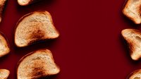 Golden crispy toast slices scattered on deep red background, creating contrast between warm bread and rich burgundy surface, food photography layout.