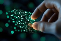 Hand touching glowing green digital particles and data streams representing technology, innovation, artificial intelligence and digital transformation.