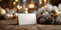 Blank white card with festive Christmas decorations, pine cones and golden ornaments on rustic wooden table with warm bokeh lights for holiday greetings.