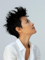 Young Asian woman with spiky black hair in white shirt looking up thoughtfully against light background, profile view showing natural beauty and confidence.