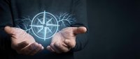 Hands holding glowing compass rose with branches, representing direction, guidance, and navigation for business strategy and decision-making concepts.