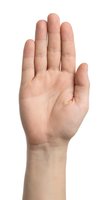 Human hand raised in stop gesture showing palm and fingers on white background isolated for design and communication concepts.