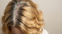 Blonde woman with dark roots showing hair regrowth and styling needs for salon and beauty treatments.
