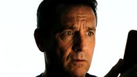 Middle-aged Caucasian man with concerned expression holding smartphone in dramatic lighting for communication and technology concepts.