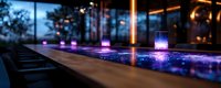 Modern bar counter with glowing neon lights reflecting on polished surface at night, creating atmospheric ambiance with purple and blue illumination in luxury venue.