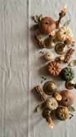 Autumn flat lay with colorful pumpkins, brass candlesticks, cinnamon sticks and dried leaves on neutral linen background for seasonal home decor and styling.