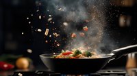 Dramatic food preparation scene with vegetables flying out of a hot pan with steam and motion blur, capturing professional cooking technique in dark setting.