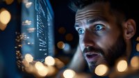 Young bearded Caucasian man with intense blue eyes illuminated by night city lights and bokeh effects, expressing wonder and amazement while looking at urban skyline.