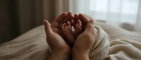 Adult hands cradling newborn baby feet wrapped in soft blanket, tender parenting moment for family, maternity, and childcare concepts.