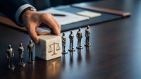 Businessman hand placing wooden cube with justice scales symbol near miniature people figures on office desk representing legal consulting and law services.