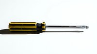 Yellow and black screwdriver with flathead tip isolated on white background for tool and hardware projects.