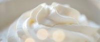 Creamy white whipped cream swirl with soft texture and golden highlights for dessert topping, baking recipes, and culinary photography applications.