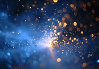 Magical glowing particles with golden and blue bokeh lights creating ethereal atmosphere against dark background. Abstract festive backdrop for celebrations.
