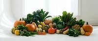 Fresh autumn harvest display with pumpkins, squash, kale and seasonal vegetables arranged on white surface for healthy eating and fall cooking concepts.