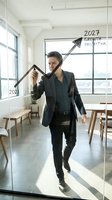 Professional businessman drawing upward growth arrow on glass wall showing 2027 projection in modern office space for business planning presentations.